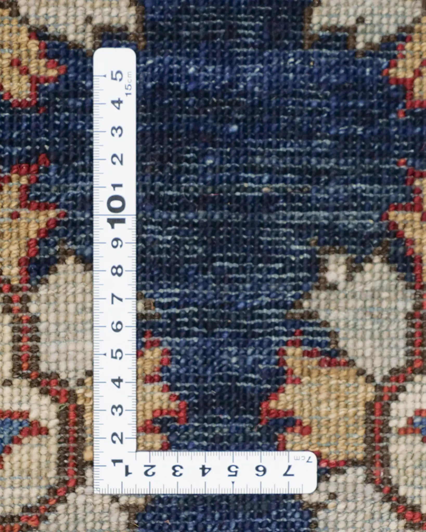 ネイビーブルーの背景に花文様が映えるアフガンラグの織りの細かさ