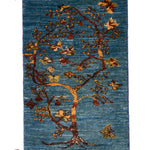 青い背景に生命力あふれる一本の木が描かれたギャッベ