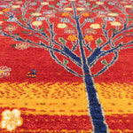 赤い背景に、青い幹と黄色や青の花が映える生命の樹デザインのギャッベ