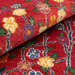 温かみのある赤色を背景に、花と枝が細やかに表現されたギャッベ絨毯