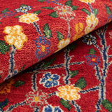 温かみのある赤色を背景に、花と枝が細やかに表現されたギャッベ絨毯