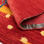 花々が全体に広がる赤色ベースの手織りラグ