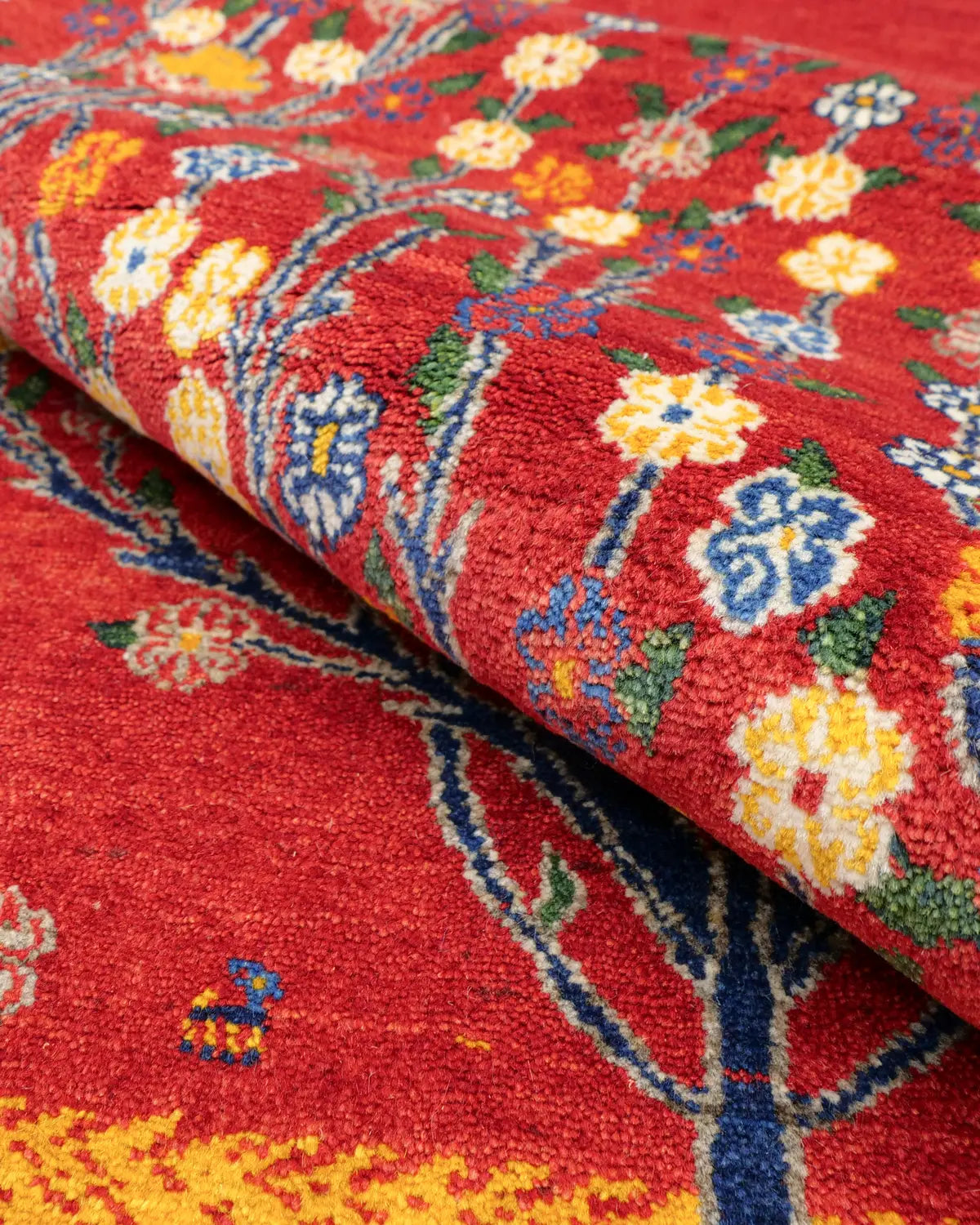 赤地に生命の樹と小花が織り込まれた、温もりある手織り絨毯