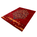 深みのある赤地に、色とりどりの花をつけた一本の木が描かれた手織りラグ