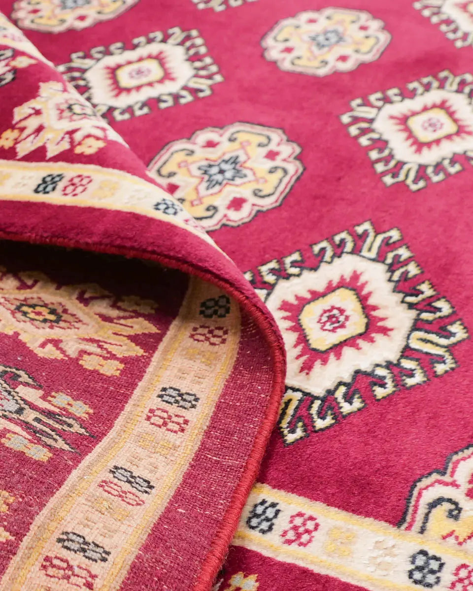 赤を基調としたパキスタン絨毯。中央にはひし形のジャルダン柄と楕円形のボハラ柄が交互に並び、周囲は繊細な模様で縁取られている。