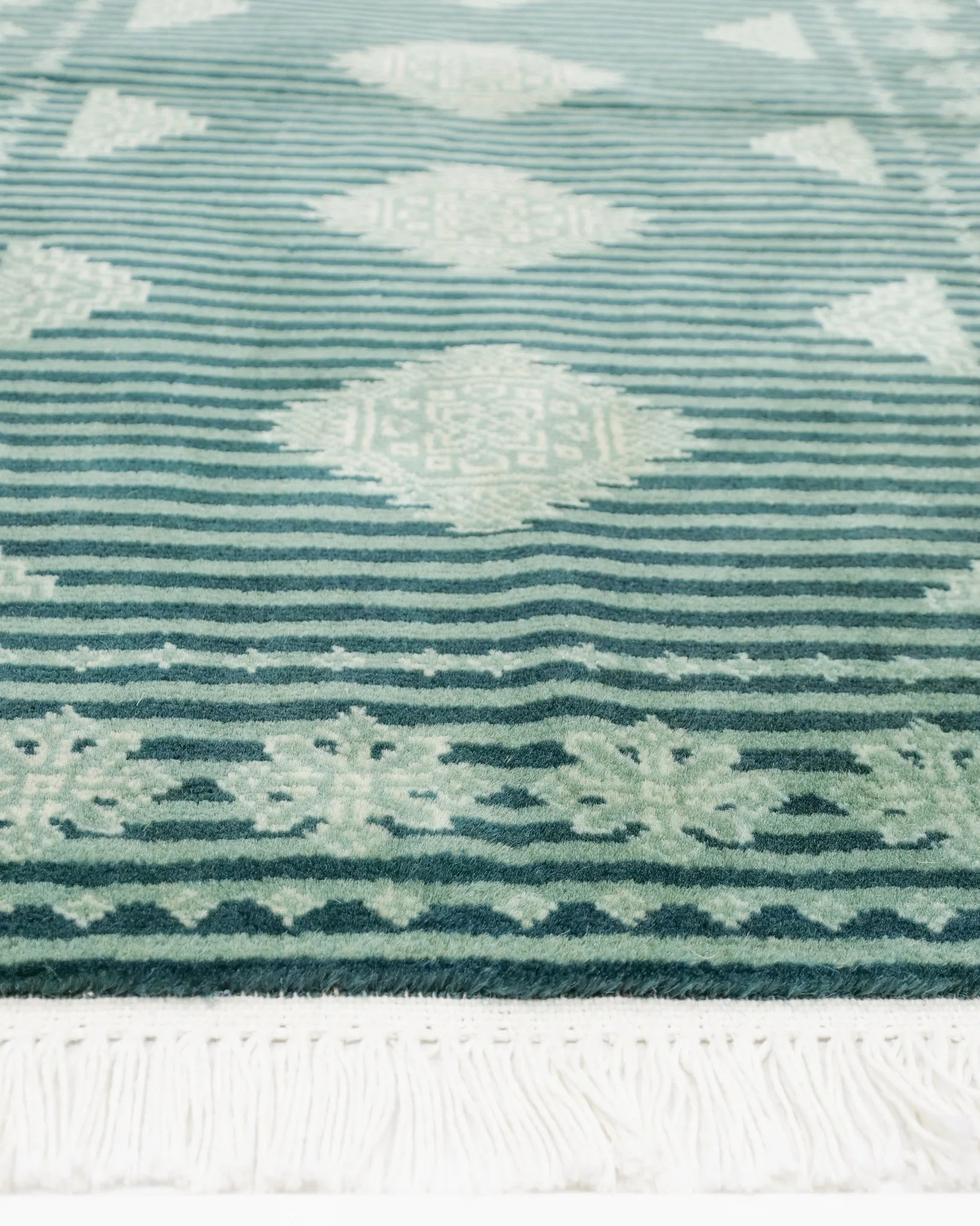 パキスタン・ラホール産のウール絨毯を広げた全体写真。深緑のストライプとジャルダール柄が並ぶ。