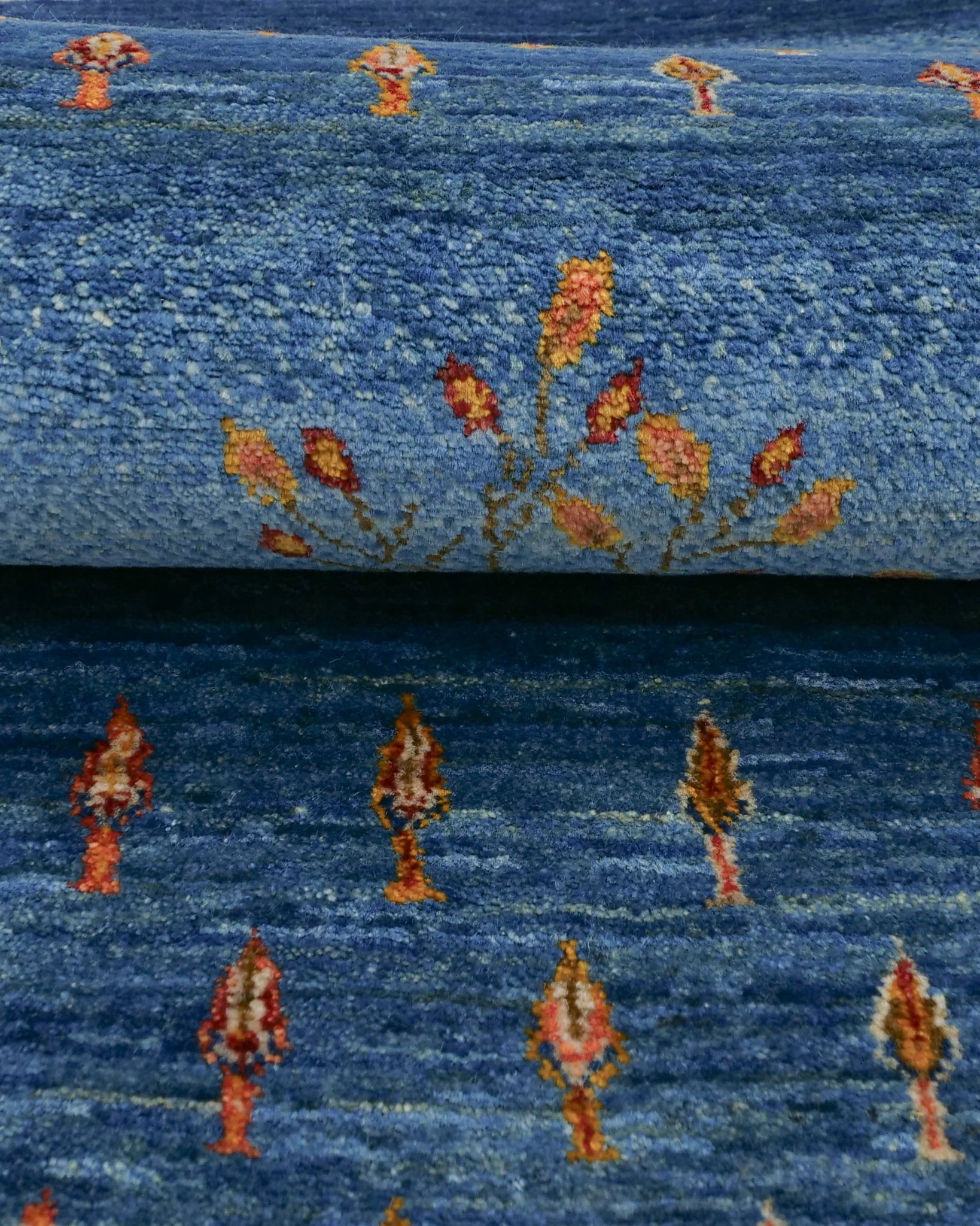 青地に枝先の花と実が描かれたギャッベ