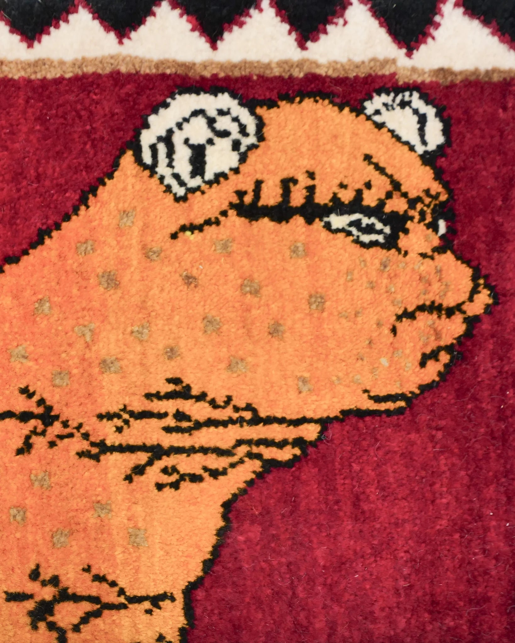オレンジ色のライオンの顔をクローズアップ。細かな斑点模様と黒の輪郭線で描かれた表情がユニークで、シーラーズ産ギャッベの繊細な手仕事の魅力が伝わるディテールショット。