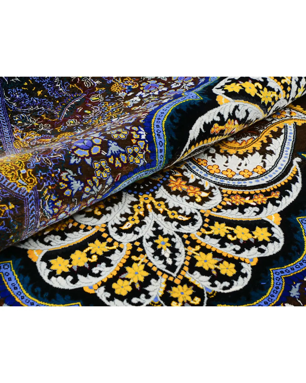 シルクペルシャ絨毯を折り重ねた状態 黒地に黄色の花と白い唐草が浮かぶメダリオン中央部の質感