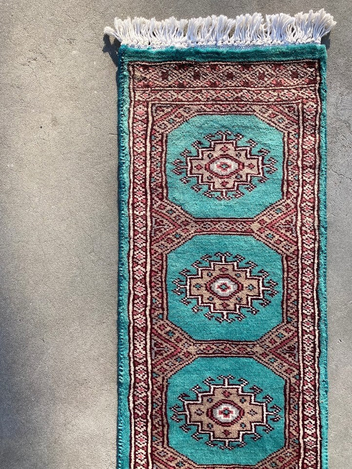 : エメラルドグリーンのベースカラーが美しい、パキスタン生産のウール絨毯。手織りの細工が際立つデザイン。