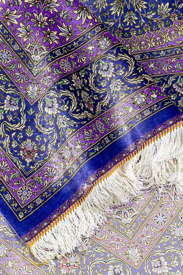 イラン・クム製、手織りのファインクオリティペルシャ絨毯。商品番号 43745。シルク素材、約101cm x 103cmのサイズ（フリンジを含まず）。正方形に近く、パープルの色合わせのデザイン。中央のレンゲ風メダリオンとその周囲の白い花や唐草模様が細かく緻密に織り込まれている。絨毯の光沢