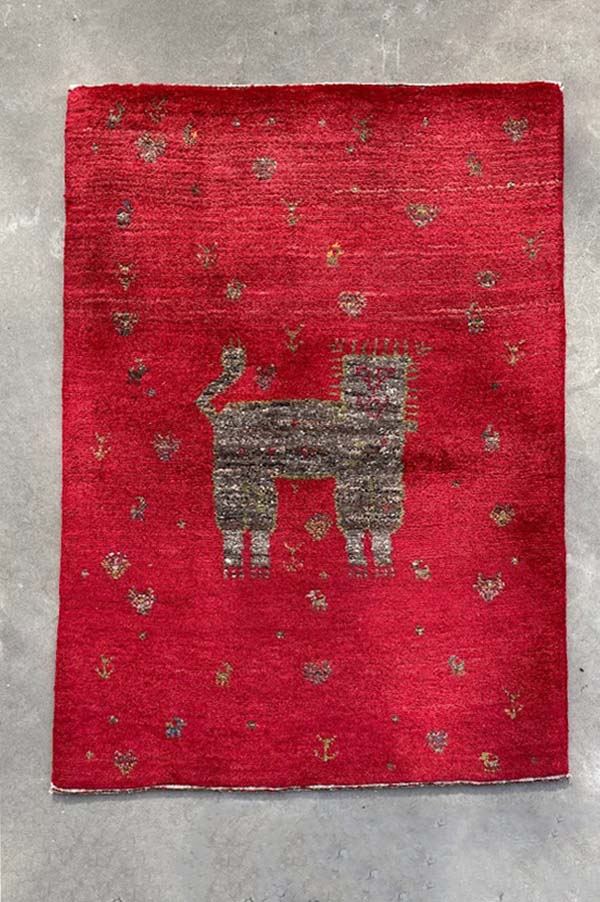 赤色のベースにライオンや鹿が描かれたペルシャギャッベ - 家庭円満と家族の願いが込められたデザイン