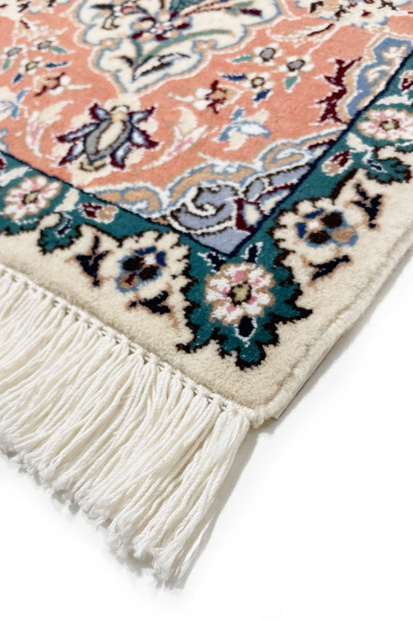 イラン・ナイン製のペルシャ絨毯ウール&シルクの手織り絨毯。サーモンピンクとターコイズグリーンの模様が特徴。