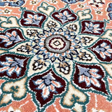 ペルシャ・ナイン製のペルシャ絨毯ウール&シルクの手織り絨毯。サーモンピンクとターコイズグリーンの模様が特徴。